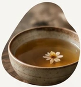 A ceramic cup of amber tea with a floating flower