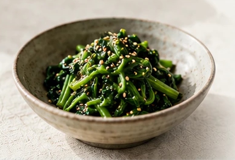 Seasoned spinach with toasted sesame seeds in a speckled stoneware bowl